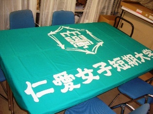テーブルに広げた仁愛女子短期大学旗の写真